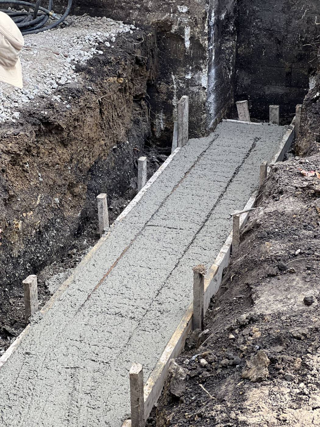 Freshly poured footing in a deep trench against the house