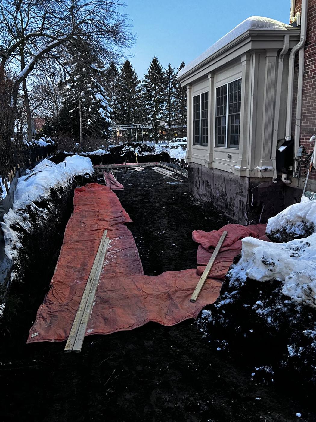 Insulated blankets laid in the footing trench with snow on both sides